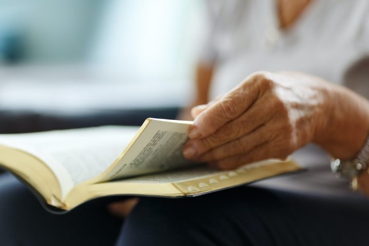 Closeup of senior woman's hands on bible, folded in prayer