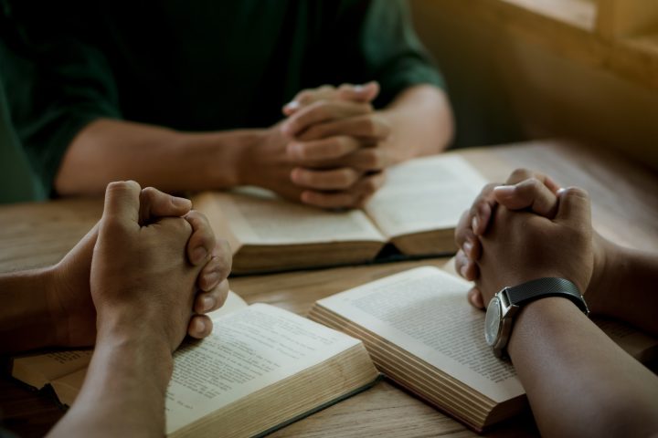 Group of christian people reading and study bible in home and pray together.
